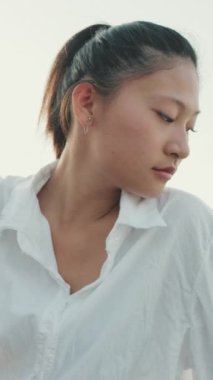 VERTICAL VIDEO:Young woman looking away while sitting in port