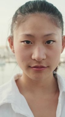 VERTICAL VIDEO: Close up, young woman looking at the camera and laughing