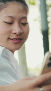 Kürsüde oturan ve cep telefonu kullanan genç bir kadının yakın çekimi.