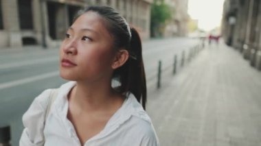 Yaklaş, genç kadın caddede yürür ve etrafa bakar.