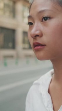 VERTICAL VIDEO: Young woman waiting for taxi