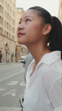 VERTICAL VIDEO: Young woman crossing the road at crosswalk