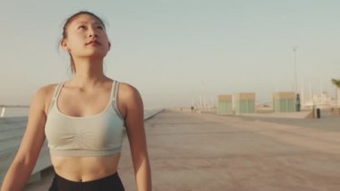 Asian girl in sports top walking outside at morning time