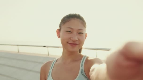 Smiling Asian Girl Sports Top Makes Selfie While Standing Embankment — Stockvideo