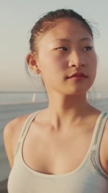 VERTICAL VIDEO: Close up, asian girl in sports top walking outside at morning time