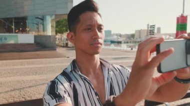 Yaklaş, genç adam rıhtımda duruyor ve cep telefonuyla fotoğraf çekiyor.