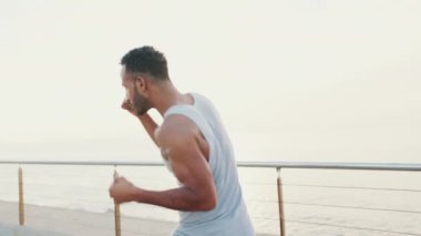 Young bearded male fit athlete boxer practicing punching technique while standing on the embankment