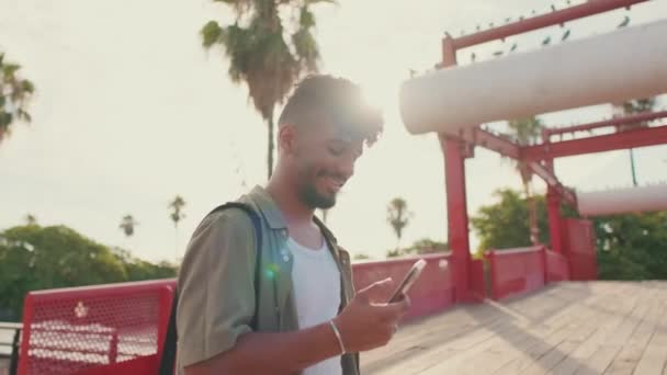 Young Smiling Man Dressed Olive Colored Shirt Walks Bridge Holding — Vídeos de Stock