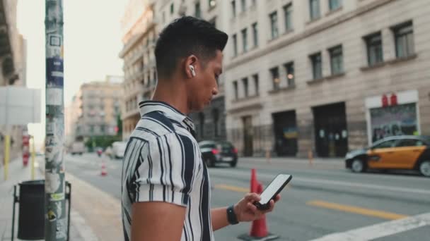 Young Man Listening Music Using Mobile Phone While Standing Crosswalk — Stockvideo