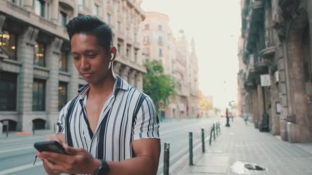 Νεαρός Περπατάει Δίπλα Στο Δρόμο Και Χρησιμοποιεί Κινητό Τηλέφωνο — Αρχείο Βίντεο