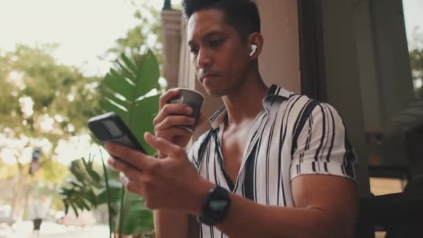 若い男が外に座って携帯電話を使う — ストック動画