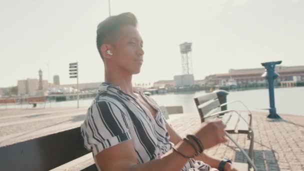 Young Man Tourist Sits Bench Pier Listens Music Backlight — Αρχείο Βίντεο