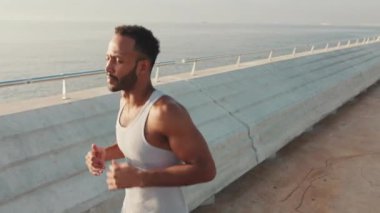 Young bearded male fit athlete runs along the promenade