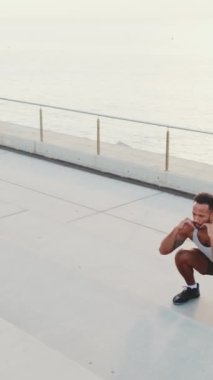 VERTICAL VIDEO: Young bearded male athlete doing workout, jumping on steps