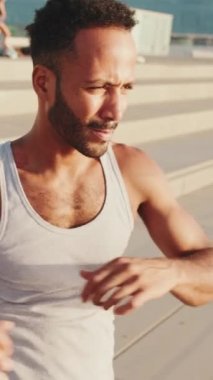 Genç sakallı erkek sporcu, setin üzerinde antrenman yapıyor, esniyor.