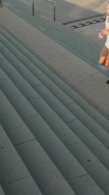 VERTICAL VIDEO: Young bearded male fit athlete doing workout, running up the steps