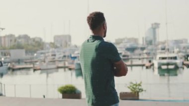 Genç adam limandaki yatlara bakıyor. Arka plan