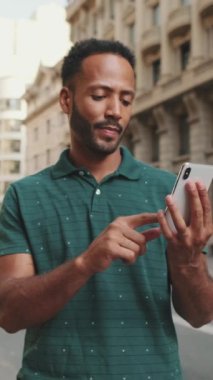 Caddenin hemen yanında duran ve telefonu kullanan genç bir adam var.