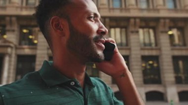 Close-up of happy young man talking on mobile phone while standing on the street