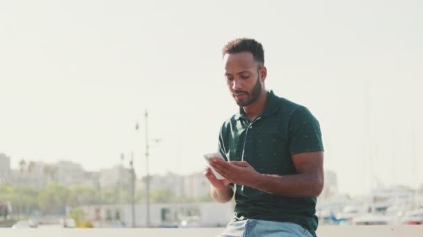 Молодий Чоловік Використовує Телефон Сидячи Гавані Яхтами Фоні — стокове відео