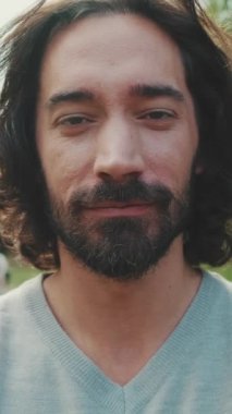 VERTICAL VIDEO: Close up, young smiling man looking at camera