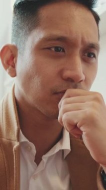 VERTICAL VIDEO: Close up, young handsome businessman wearing beige suit working with laptop in cafe