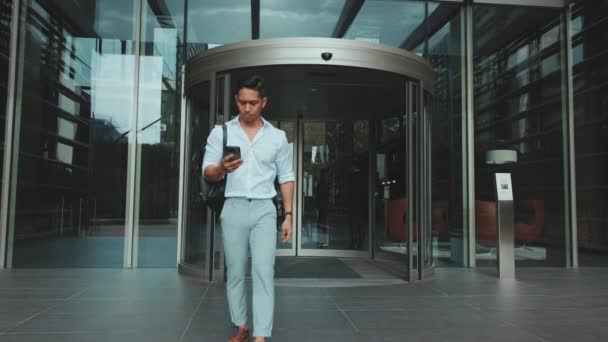 Młody Biznesmen Opuszcza Centrum Biznesowe Smartfonem — Wideo stockowe