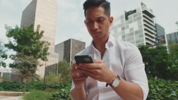 Junger Geschäftsmann Benutzt Handy Während Neben Dem Business Center Sitzt — Stockvideo