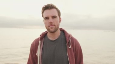 Genç adam sahilde duruyor.