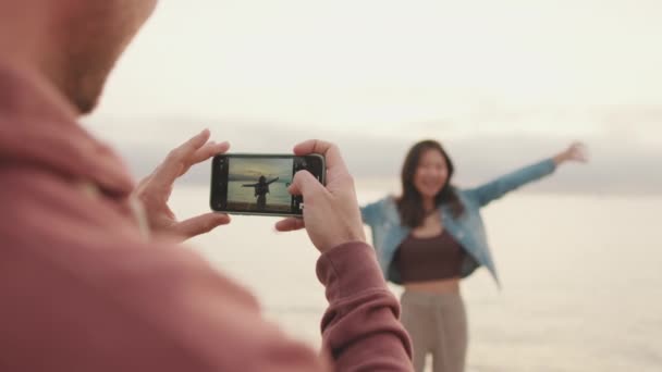 男人在岸上给女人拍照 — 图库视频影像