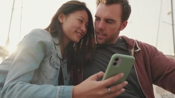 Lykkelig Par Som Sitter Havnen Ser Bilder Videoer Mobiltelefon – stockvideo