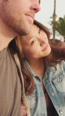 VERTICAL VIDEO: Close up, couple in love holding hands while sitting in the seaport