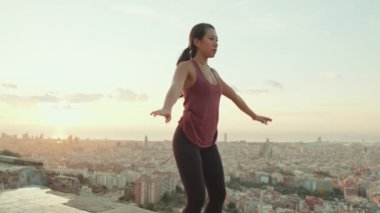 Girl practicing yoga at the lookout point at dawn