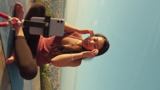 垂直ビデオ スポーツのトップの若い女性が三脚に携帯電話を使用してライブ放送しています — ストック動画