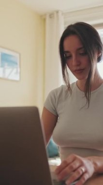 VERTICAL VIDEO: Evde dizüstü bilgisayarda çalışan genç bir kadın