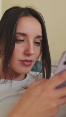 VERTICAL VIDEO, Close-up of young woman using phone while sitting on sofa at home