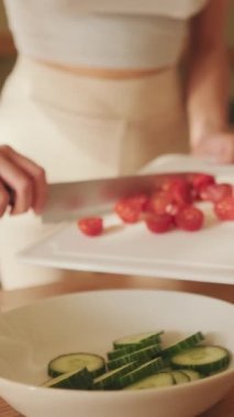 VERTICAL VIDEO, Close-up of young woman's hands preparing salad at home in the kitchen