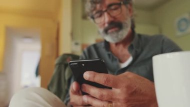 Yaşlı bir adamın cep telefonunda daktilo yazarken yakın plan fotoğrafı.
