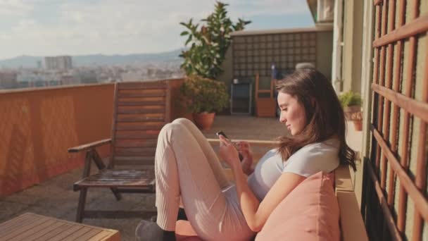 Mujer Joven Usando Teléfono Móvil Mientras Está Sentado Balcón Casa — Vídeo de stock