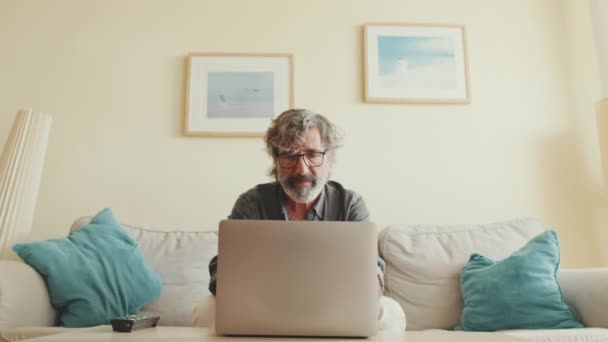 Anciano Hombre Positivo Escribiendo Ordenador Portátil Sentado Sofá Sala Estar — Vídeos de Stock