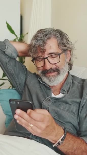 Vertical Video Elderly Positive Man Using Mobile Phone While Sitting — Stock Video