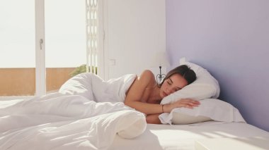 Sabahın köründe genç bir kadın yatakta uyuyor.