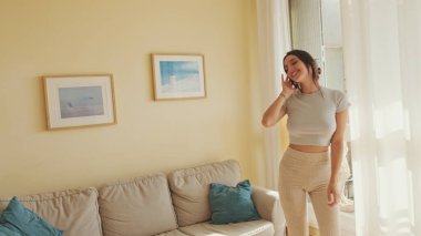 Genç ve güzel bir kadın evde dans ediyor, hafta sonunu kutluyor, eğleniyor. ileri hareket