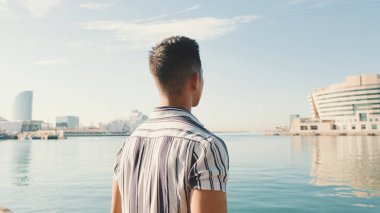 Genç adam iskelede duruyor. Arka plan