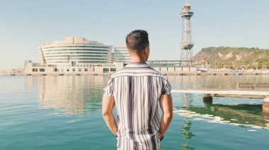 Genç adam iskelede duruyor. Arka plan