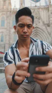 Basamaklardaki genç turist, arka planda otururken cep telefonu kullanıyor