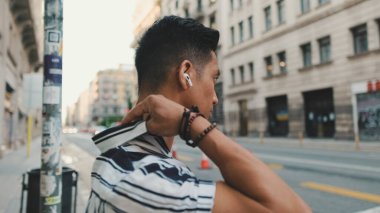 Genç adam yaya geçidinde dururken müzik dinliyor.