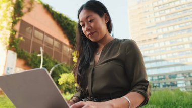 Genç kız modern binaların arka planında bilgisayar kullanıyor.