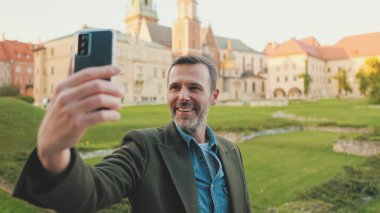 Adam eski şehrin arka planında cep telefonundan selfie çekiyor.