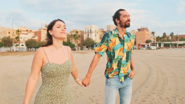 Birbirini seven bir çift kumsalda yürüyor ve sarılıyorlar.